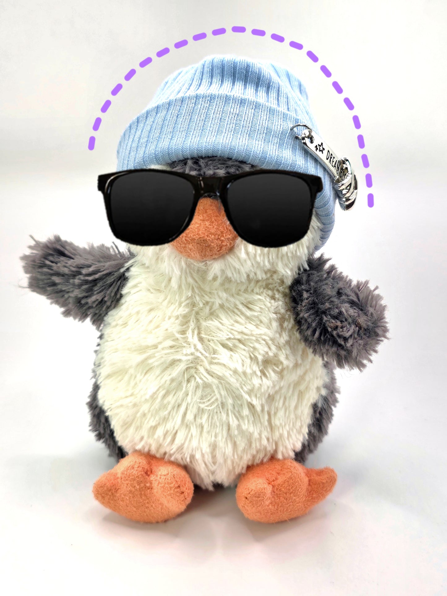 Plush toy penguin wearing sunglasses and a blue beanie on a white background