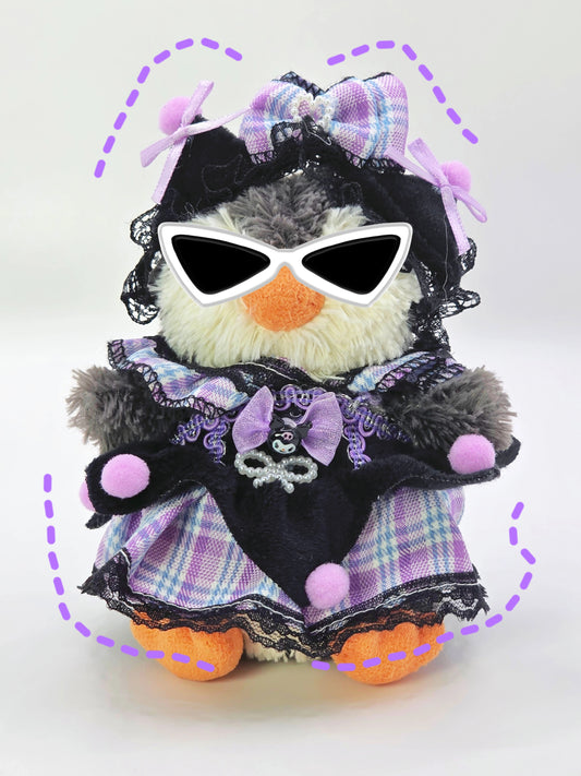 Stuffed toy penguin wearing sunglasses, a purple dress with black lace, and a bow on a white background.